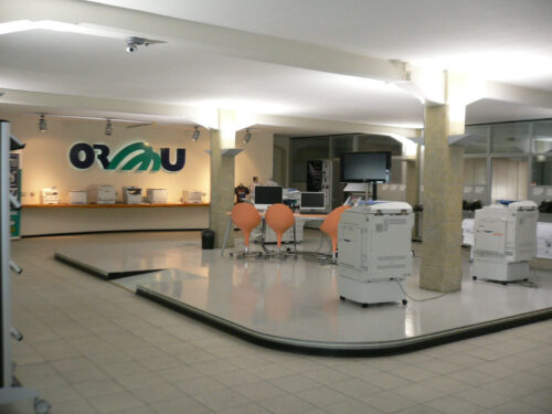 ORMU di Fenini - immagine dello showroom in via Sciascia a Parma con stampanti Ricoh in mostra e il logo ORMu sullo sfondo
